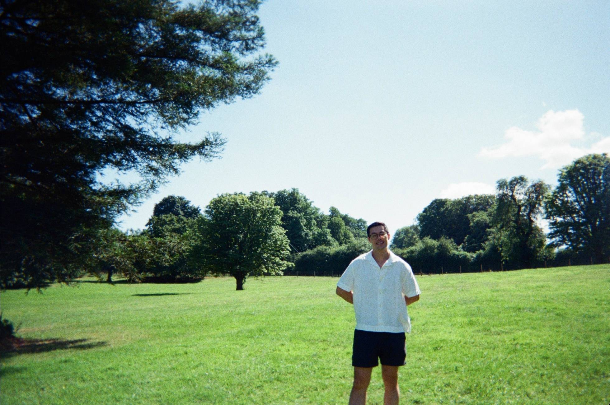 Jerry Zheng standing in a mown meadow, with tall trees behind him.